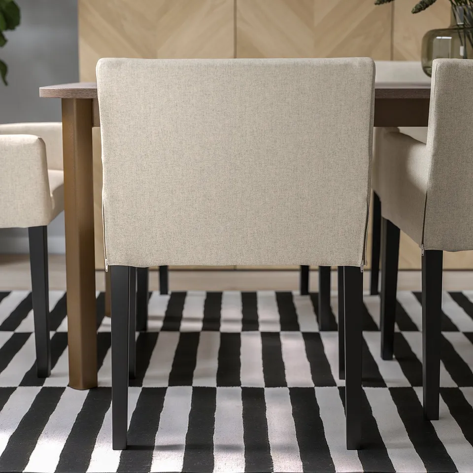 Chair with beige fabric, wooden legs, under table.