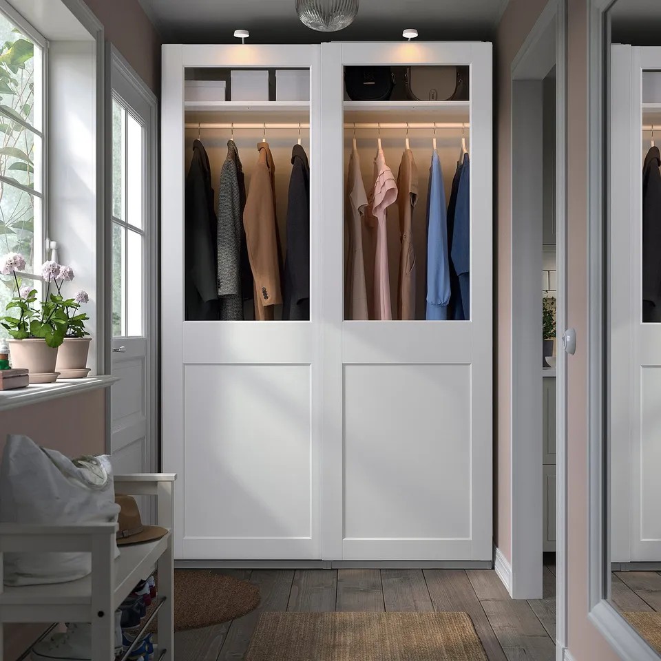 Modern white PAX wardrobe with glass doors, organised clothes.