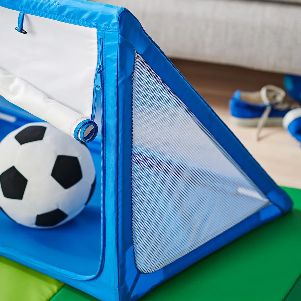 Small blue kids soft football goal, with white mesh net, on green floor, ready for play.