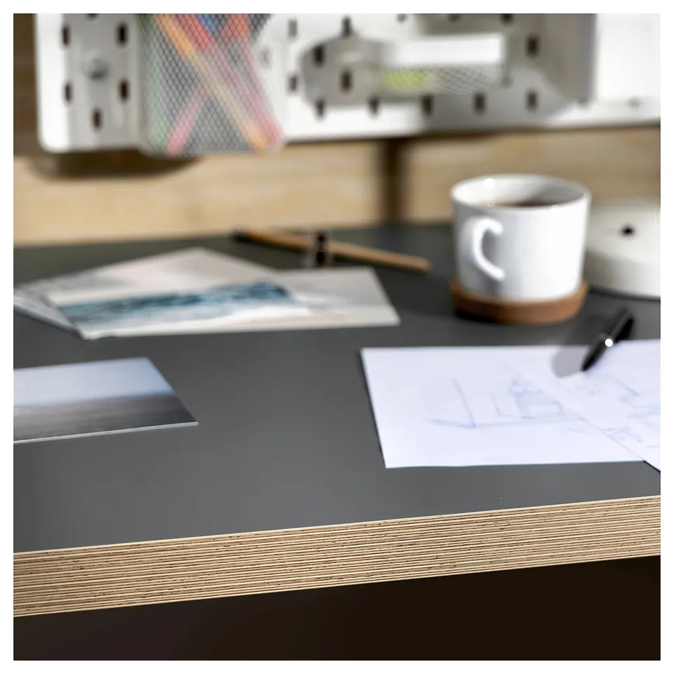 Work desk with black tabletop, white mug, papers, pen, and blurred background.