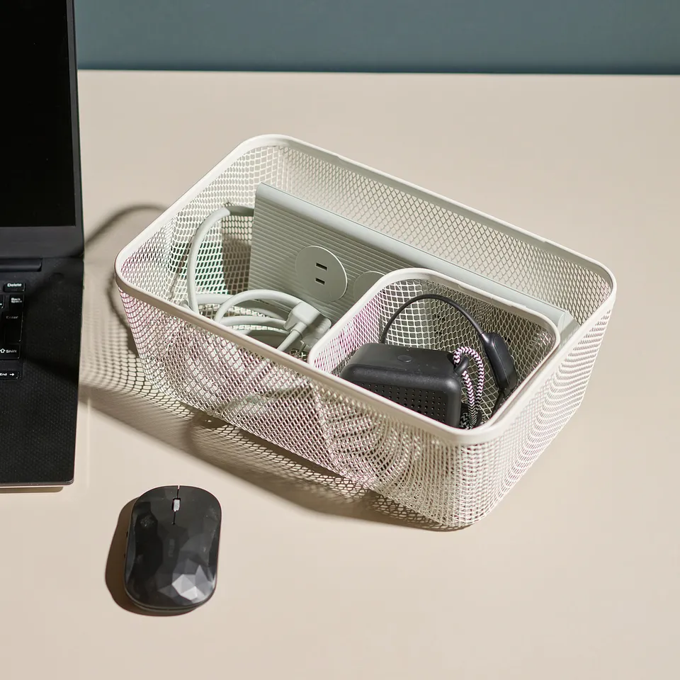 Desk organiser holding tech accessories next to laptop.