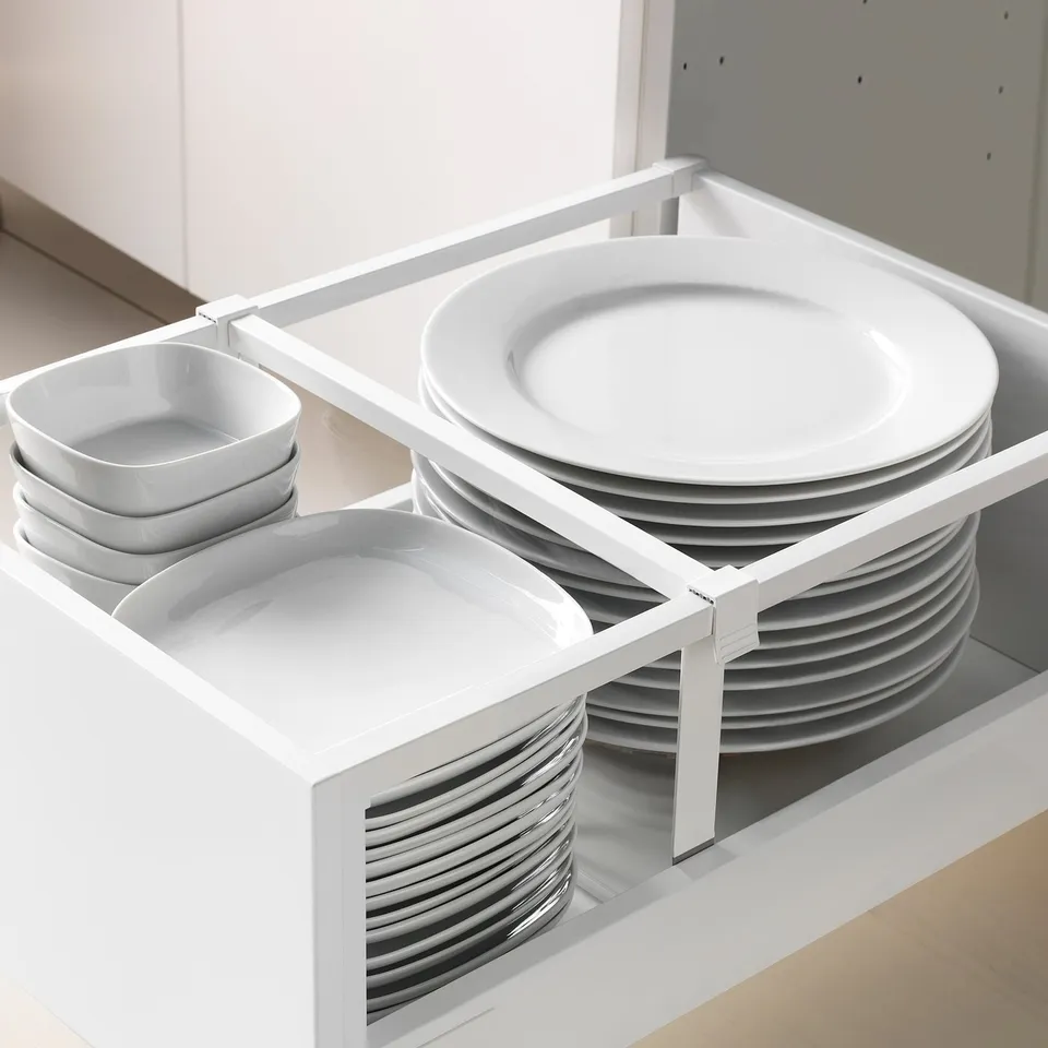 White kitchen cabinet with pull-out drawer, organising plates and bowls.