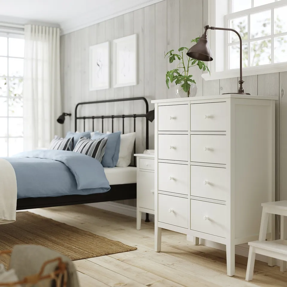 Minimalist bedroom with white GULLABERG dresser, blue bedding, natural wood floor, and greenery.