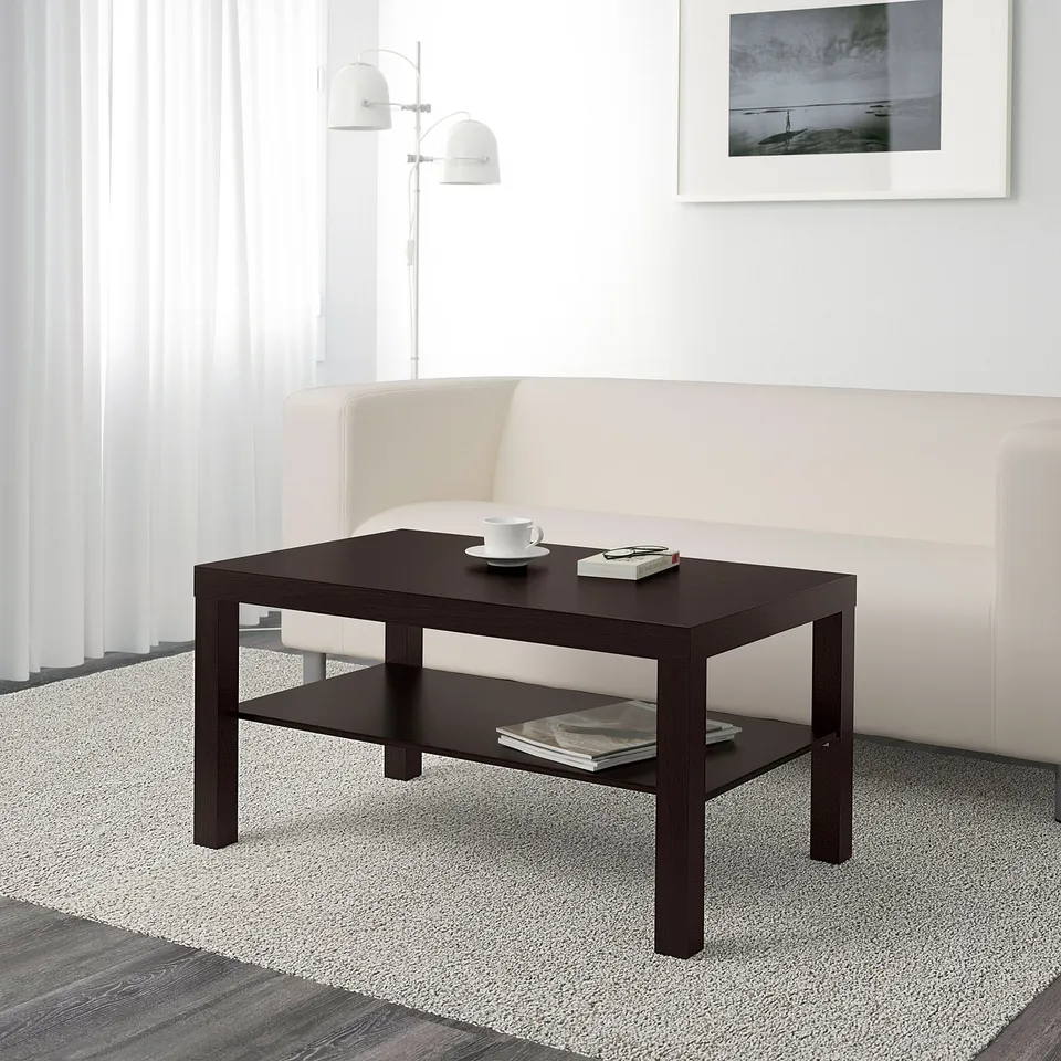 Modern living room with a white couch and dark coffee table. The table holds two cups and magazines.