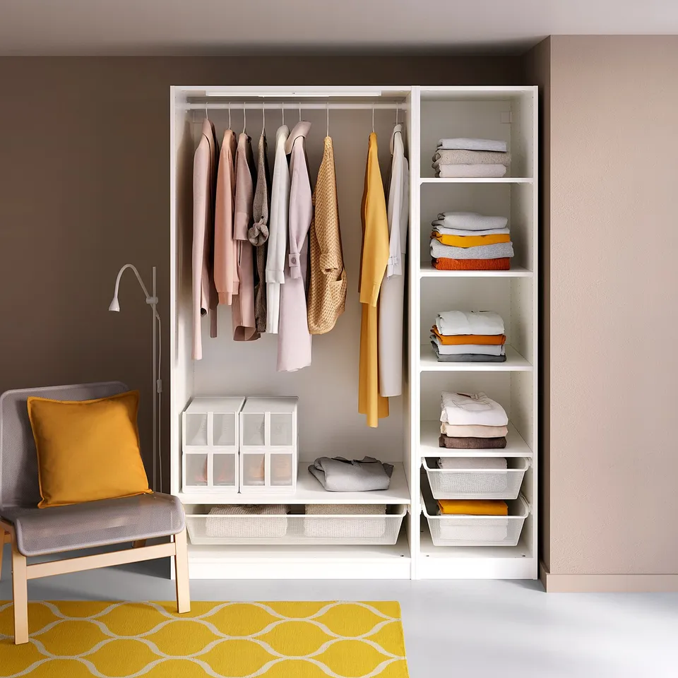 Modern walk-in closet with PAX units, clothes, chair, pillow, and rug.