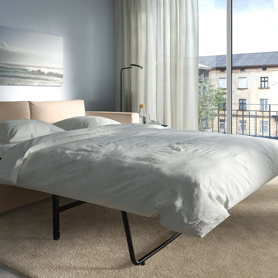 Modern bedroom with VIMLE sofa-bed near city-view window. Blue walls, light curtains, cosy carpet.