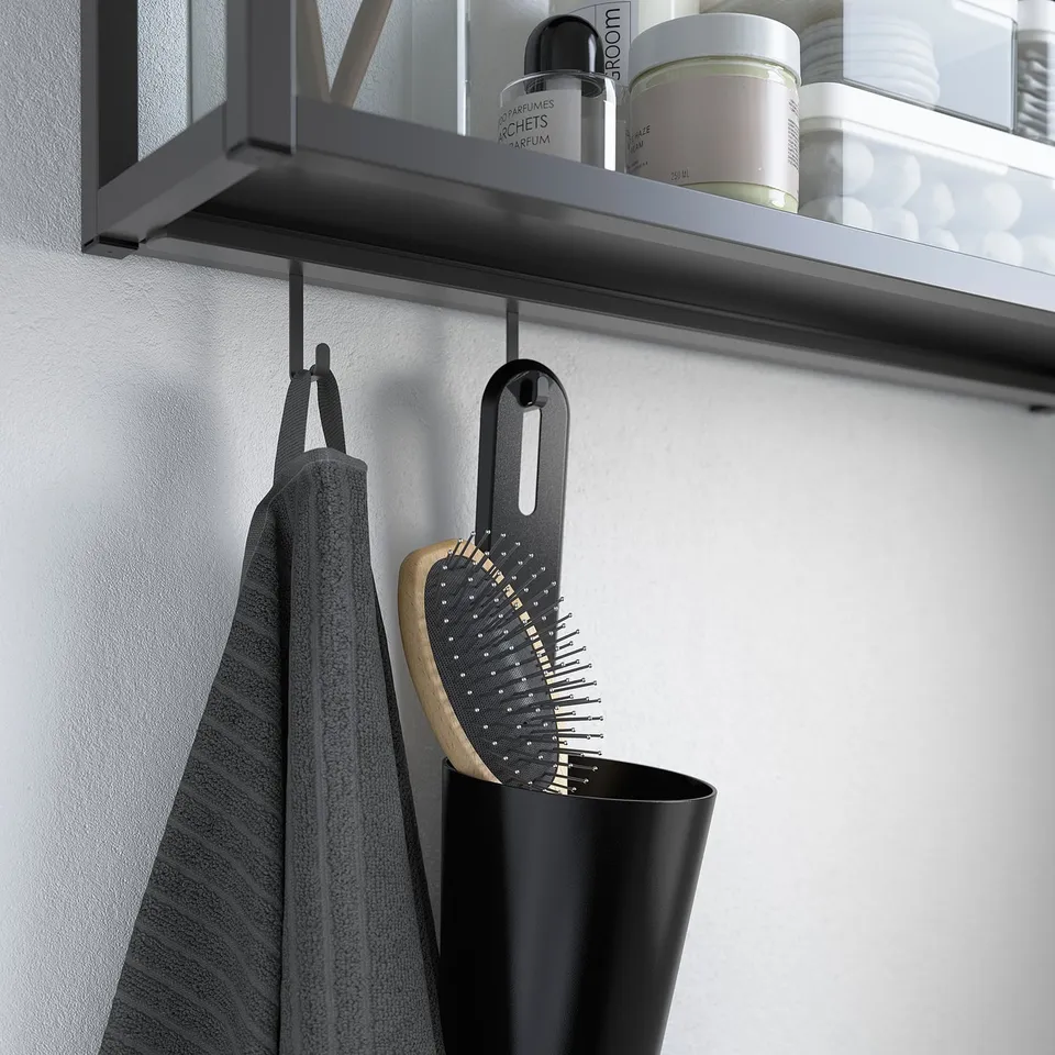 Modern bathroom shelf with ENHET rail holding grey towel, black hairbrush in container, and various toiletries.