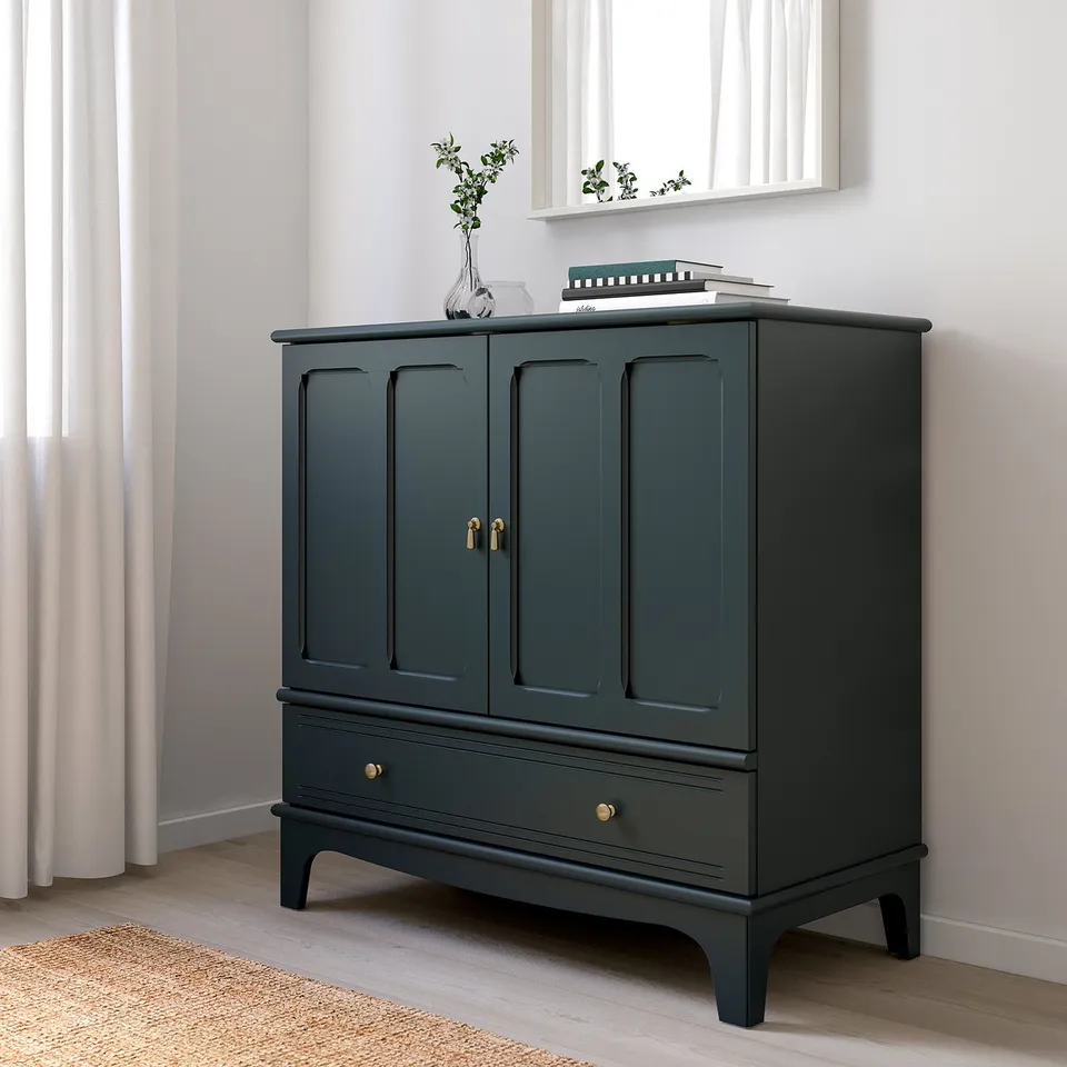 Modern dark green LOMMARP storage cabinet with gold handles. Tall, narrow, fits neatly next to window, featuring gentle close drawers and doors.
