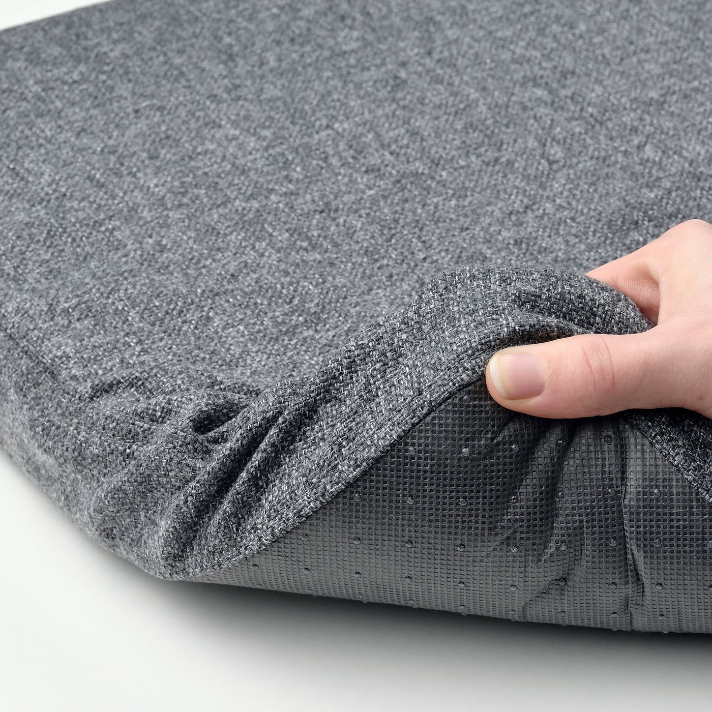 Hand holding grey fabric, showcasing soft, non-slip backing on a memory foam chair pad.
