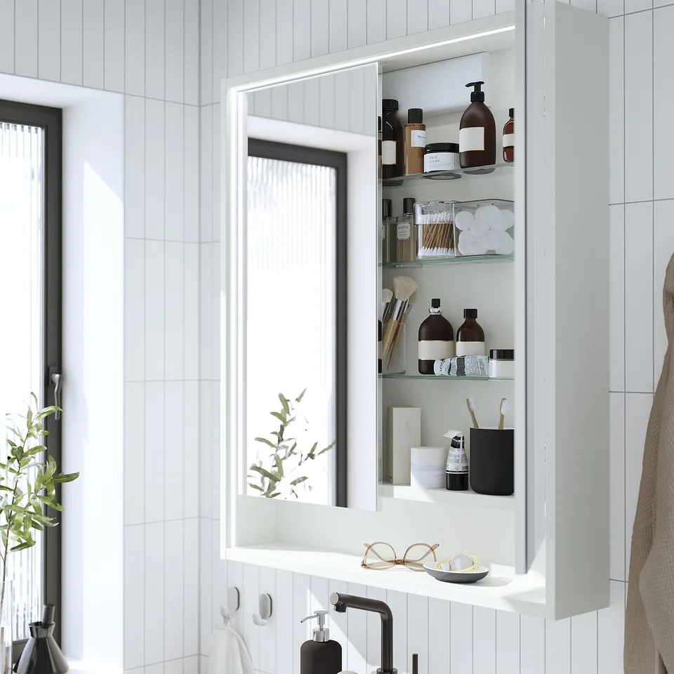 Bathroom cabinet with lighting, toiletries, and mirror.
