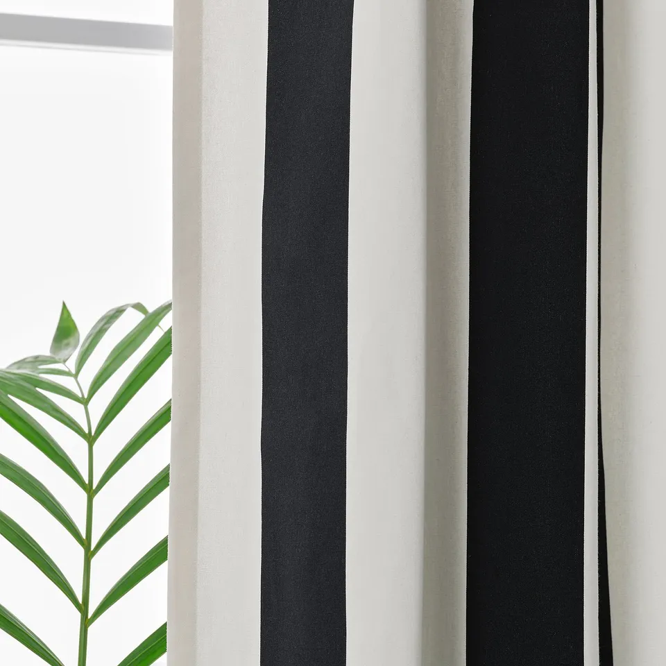 Striped curtains with black and white stripes, eyelets for easy movement, green plant nearby.