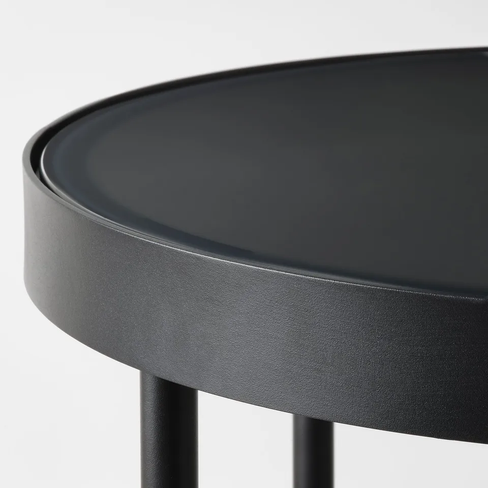 Modern black side table with smoked glass top and sleek steel legs.