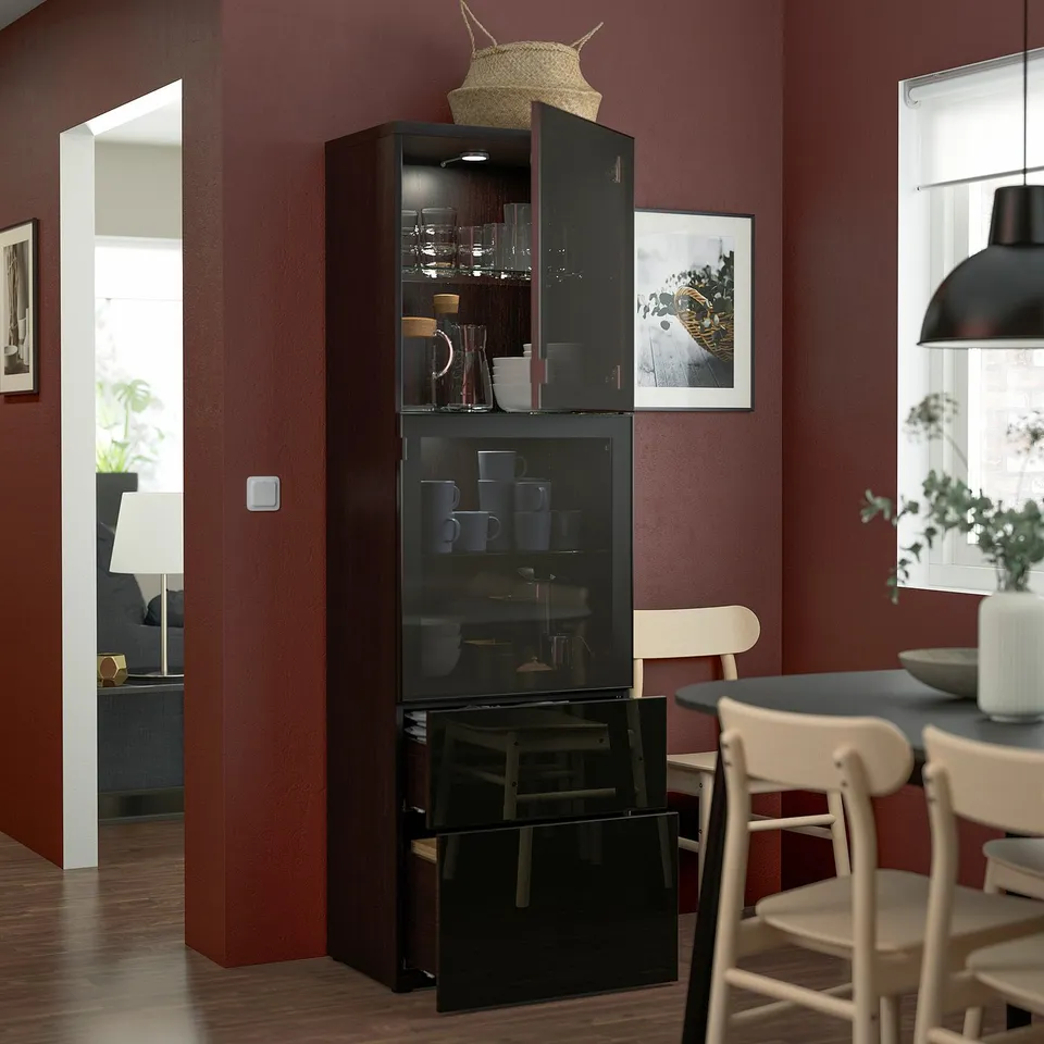 Modern room: maroon walls, BESTÅ cabinet with glassware & hat, white chair, dining table.