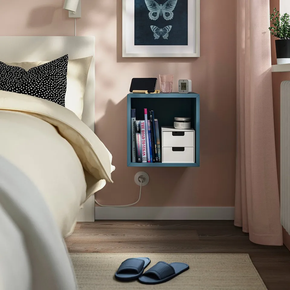 Cosy bedroom with white bed, black dot pillow, blue cabinet, slippers, butterfly print.