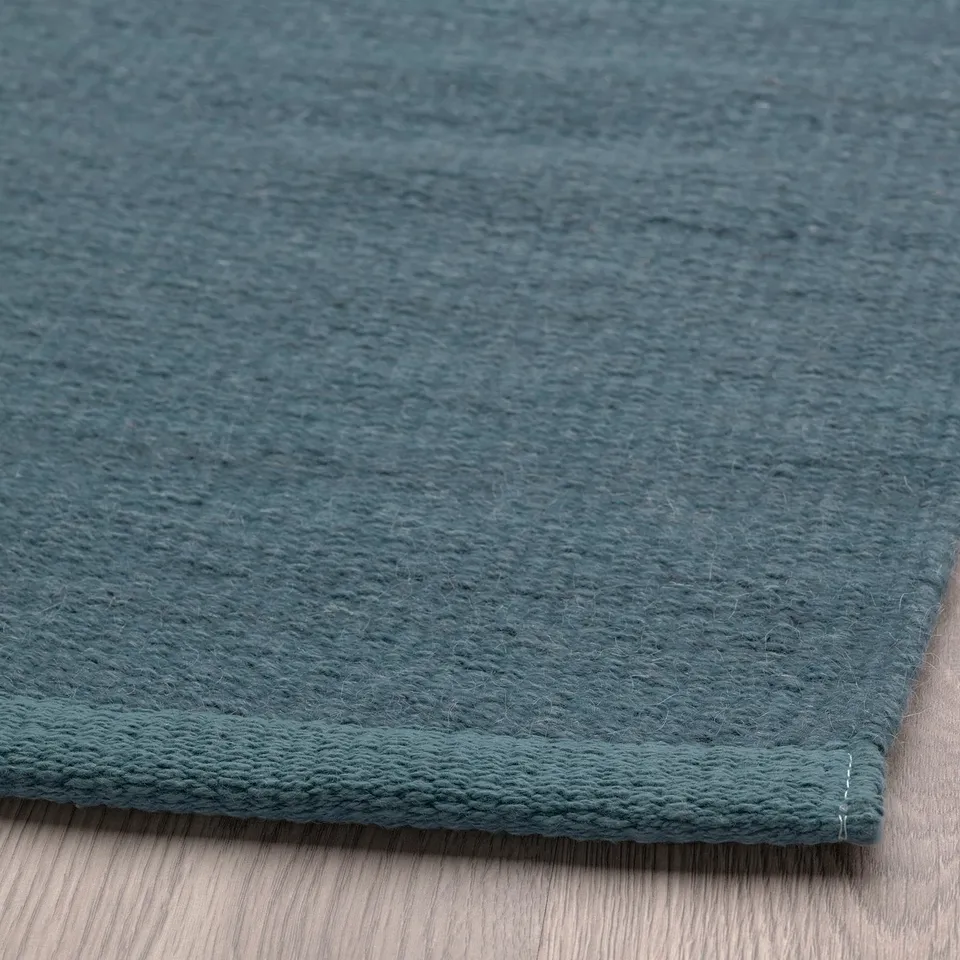 Close-up of high-quality wool rug, soft texture, gentle grey-blue shade.
