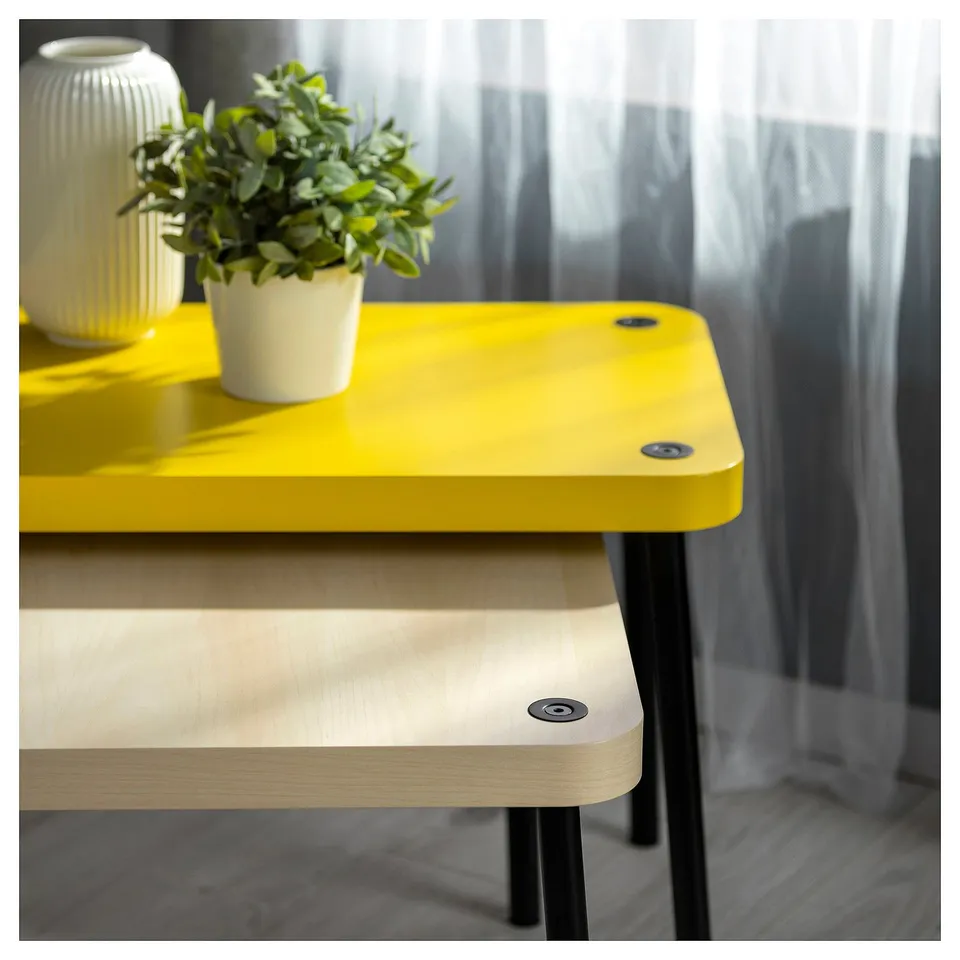 Bright yellow and wooden nest tables with metallic legs, styled with potted plants and vases.