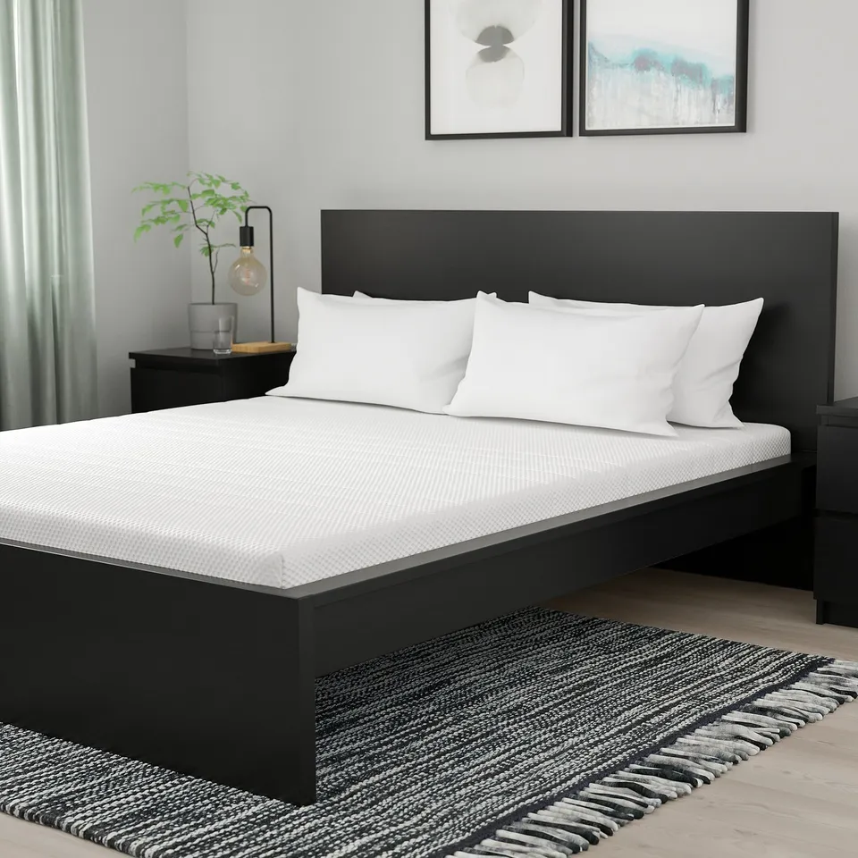 Modern bedroom: black ÅKREHAMN bed, white pillows, black nightstands, green plant, art, striped rug.