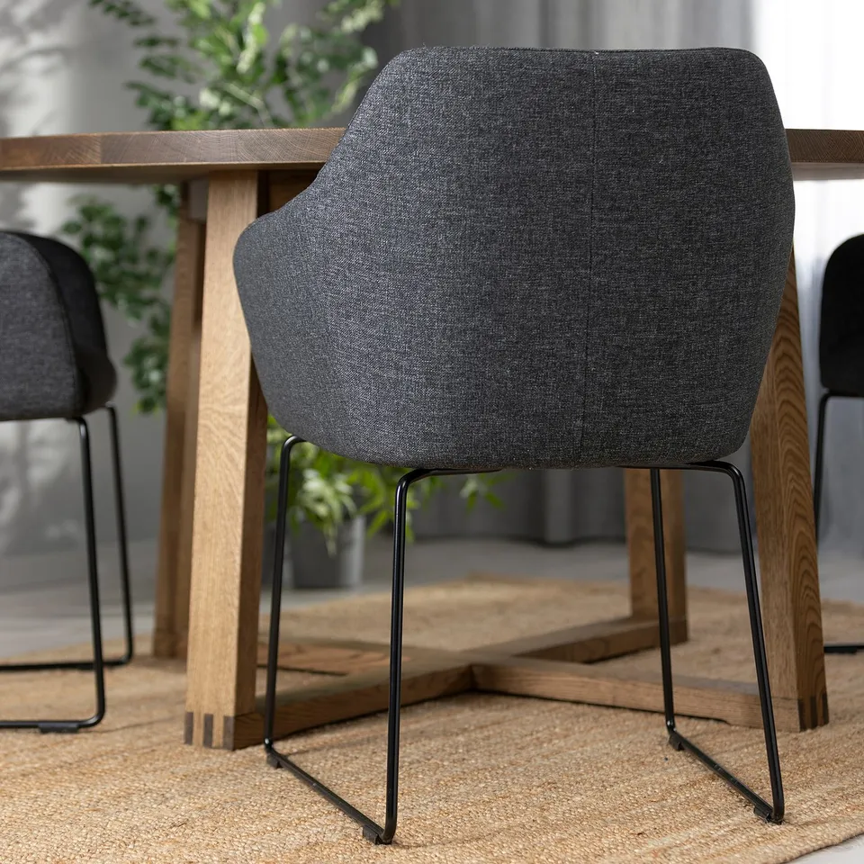 Black upholstered dining chair with metal legs around wooden table, showcasing sturdy design and comfort.
