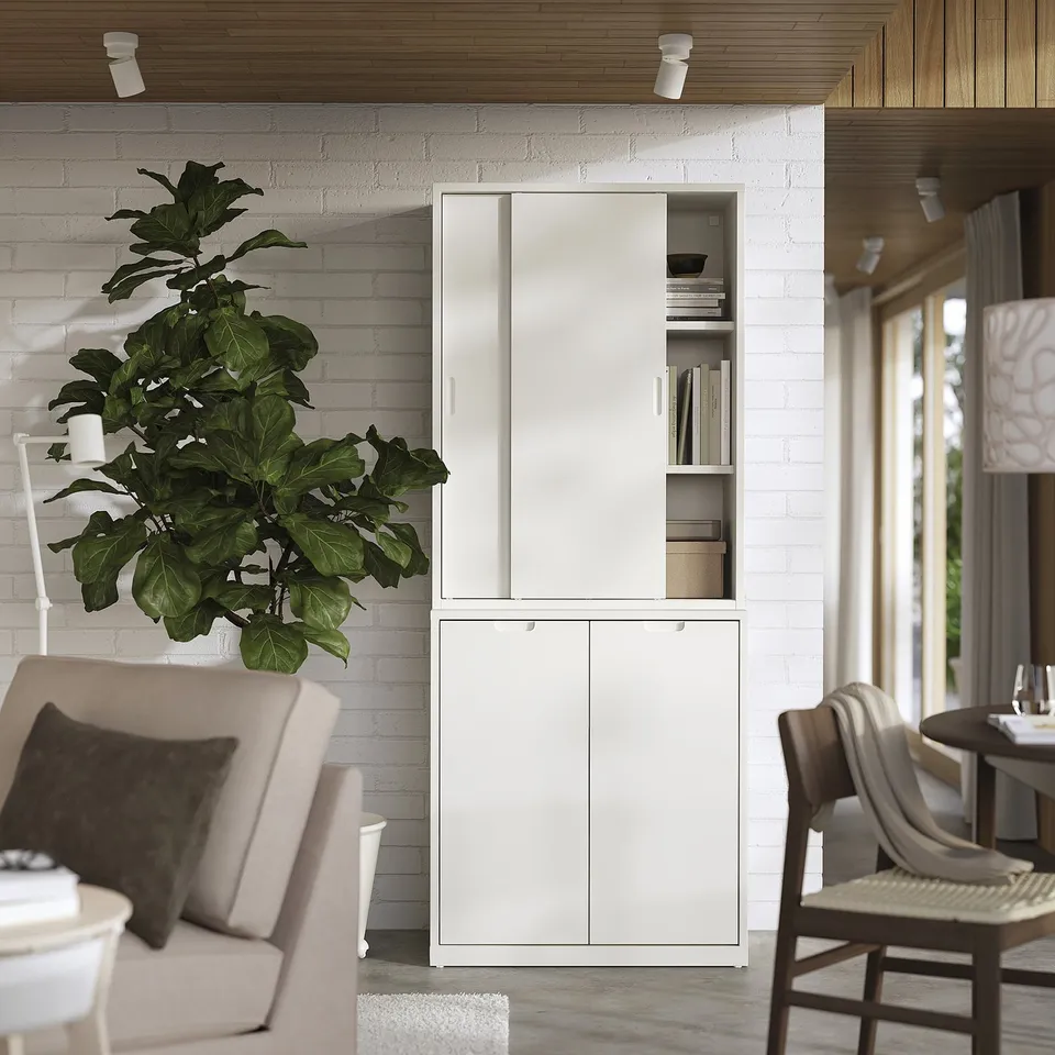 Modern living room TONSTAD off-white cabinet with soft-close doors and adjustable shelves, complementing neutral decor and a large green plant.