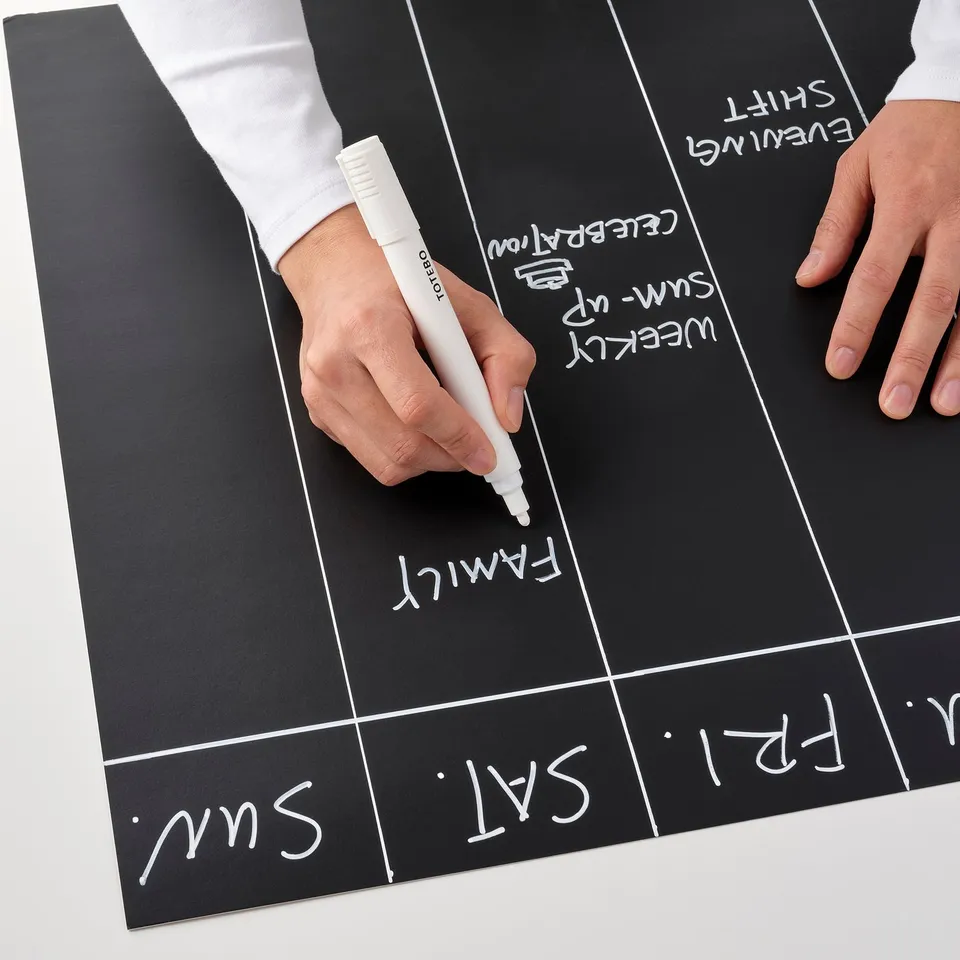 Person writes on large blackboard with white marker.