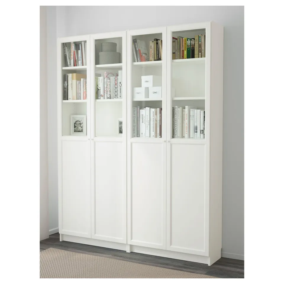 White BILLY bookcase with glass doors, displaying various books and decorative items on shelves.