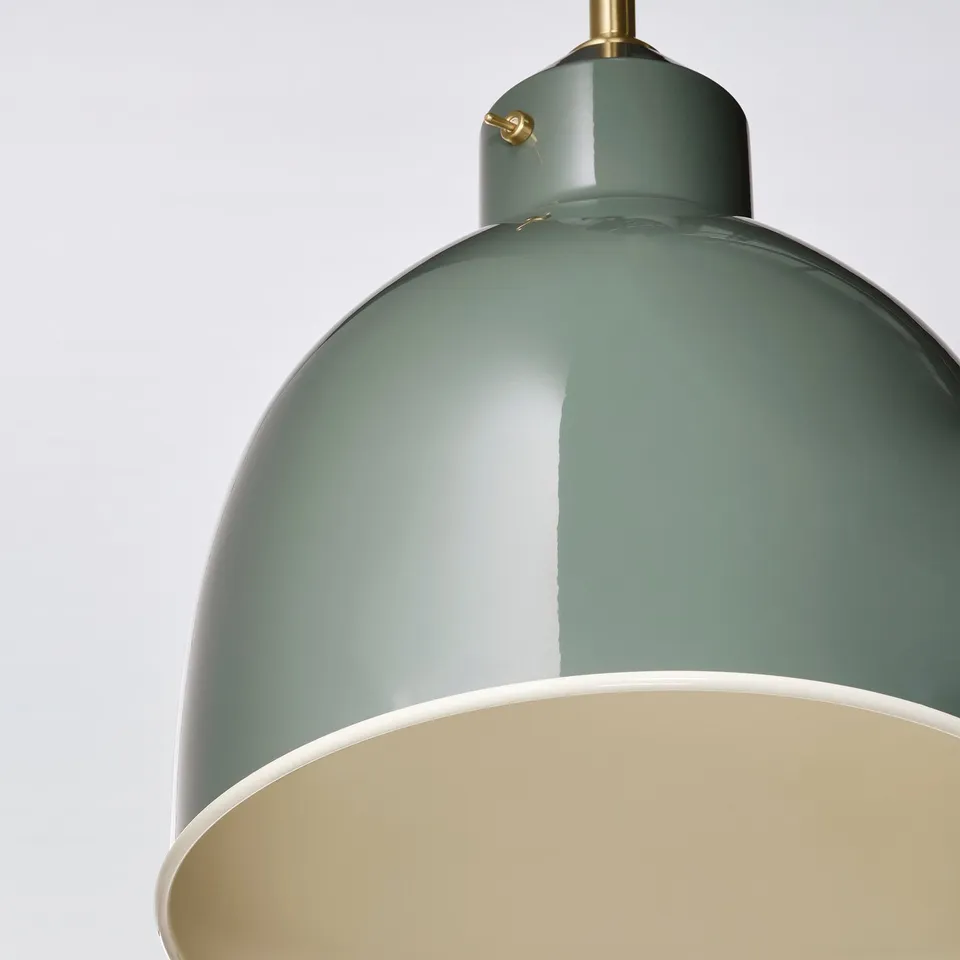 Modern pendant lamp with glossy green shade and gold accents; sleek, industrial-inspired design.