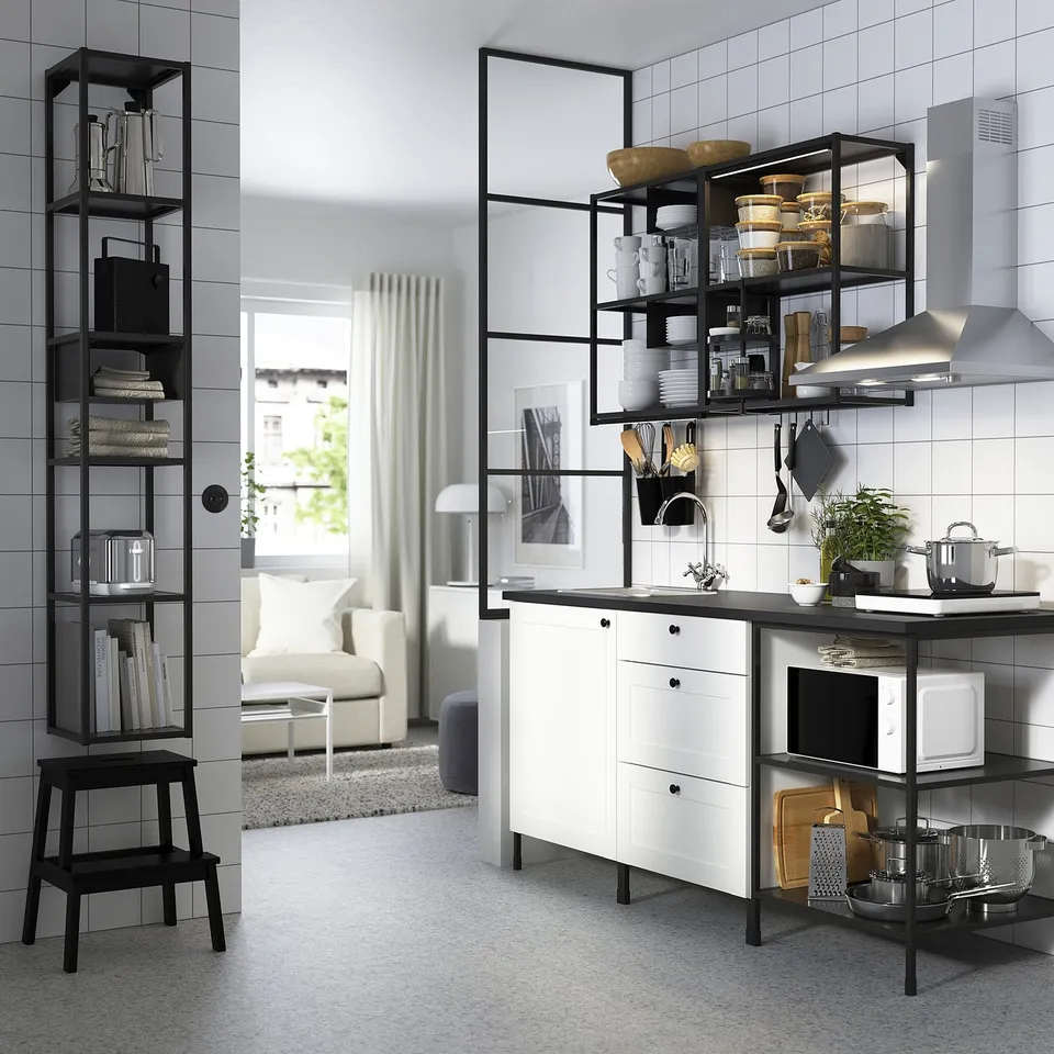 Modern kitchen with sleek black and white decor, featuring open shelving, stainless appliances, and a cosy living room area with neutral tones.