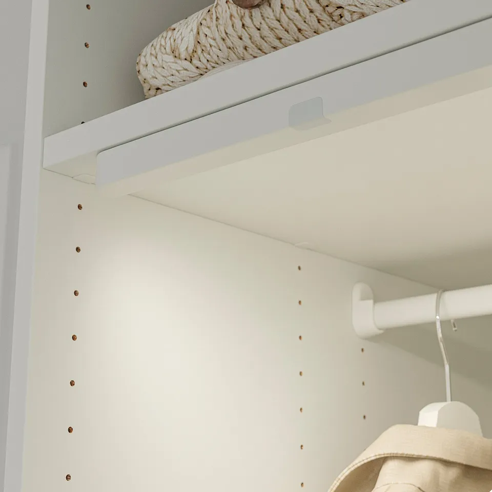 Closet with adjustable shelves, basket on top, jacket on middle rod.