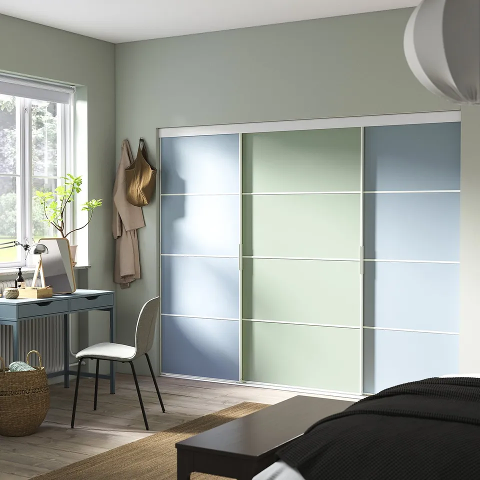 Modern bedroom with large, multi-colored, sliding closet doors and a sleek grey desk by the window.