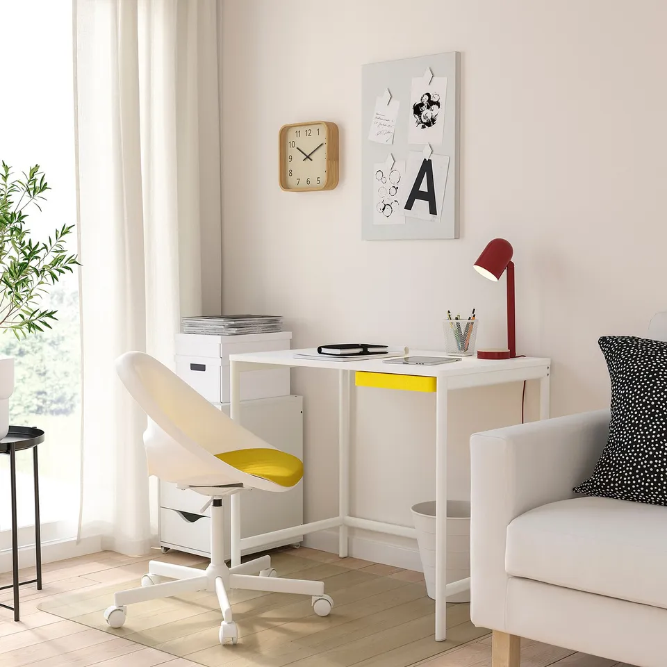 ENKROKEN desk in bright room with ergonomic chair, red lamp, clock, and plant.