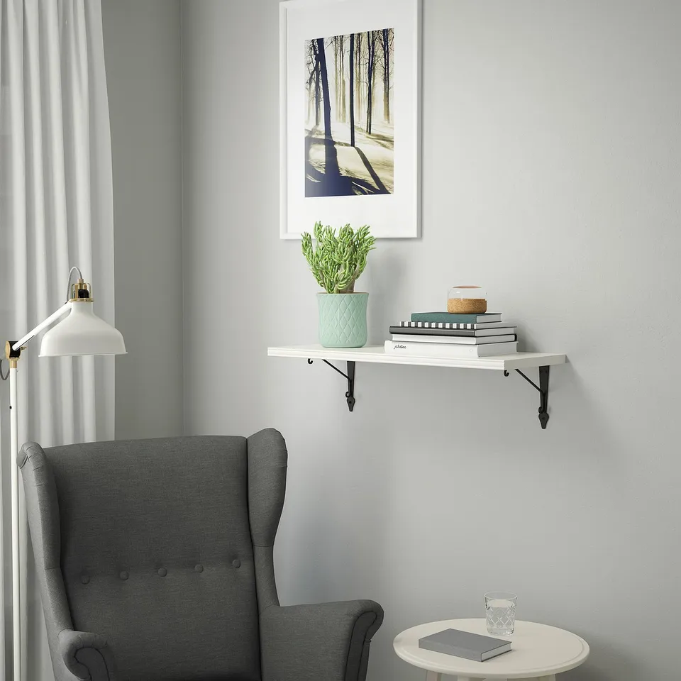 Cosy reading nook with armchair, side table, books, plant, & lamp