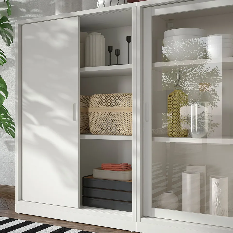 TONSTAD off-white cabinet with glass doors, modern design, sleek handles, adjustable shelves, housing decorative items.