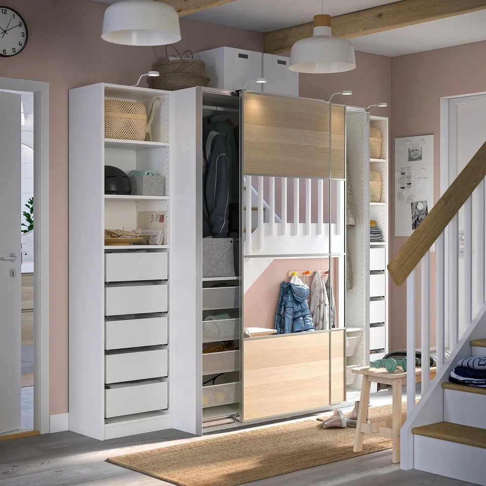 A modern white and light wood PAX wardrobe with sliding doors and organised compartments.