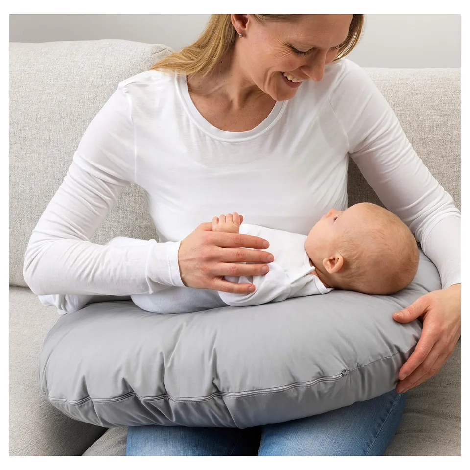 Person nurses baby with pillow.