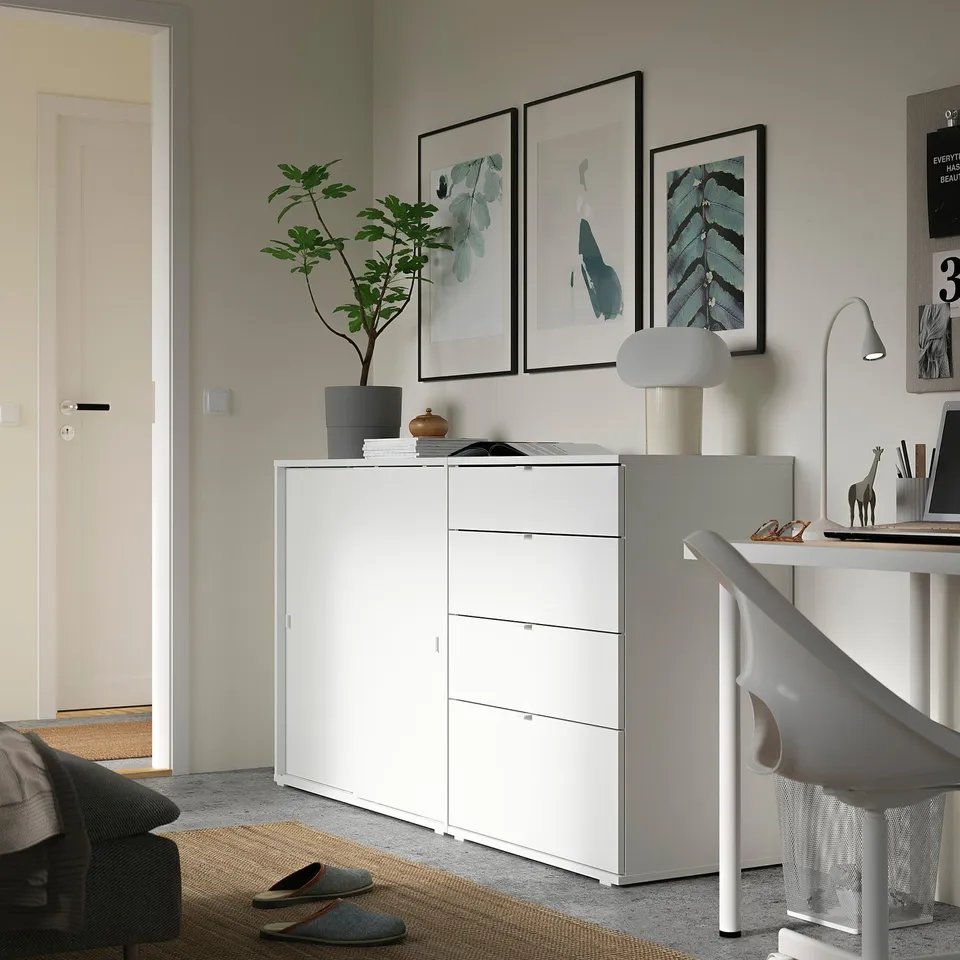 Modern office setup with white ikea VIHALS storage unit, featuring plants, lamp, and artwork on the wall.