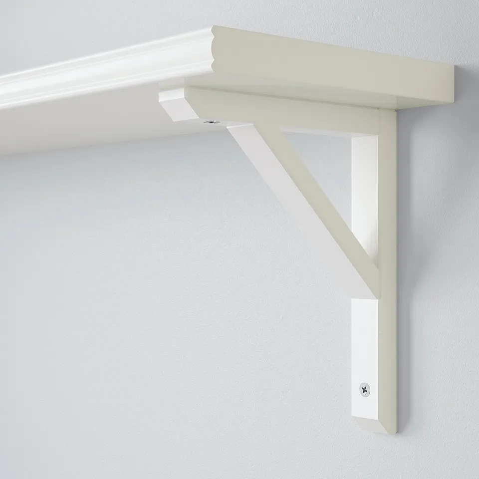 White wall-mounted shelf with bevelled edge, supported by sturdy wooden bracket, attached securely to light-colored wall.