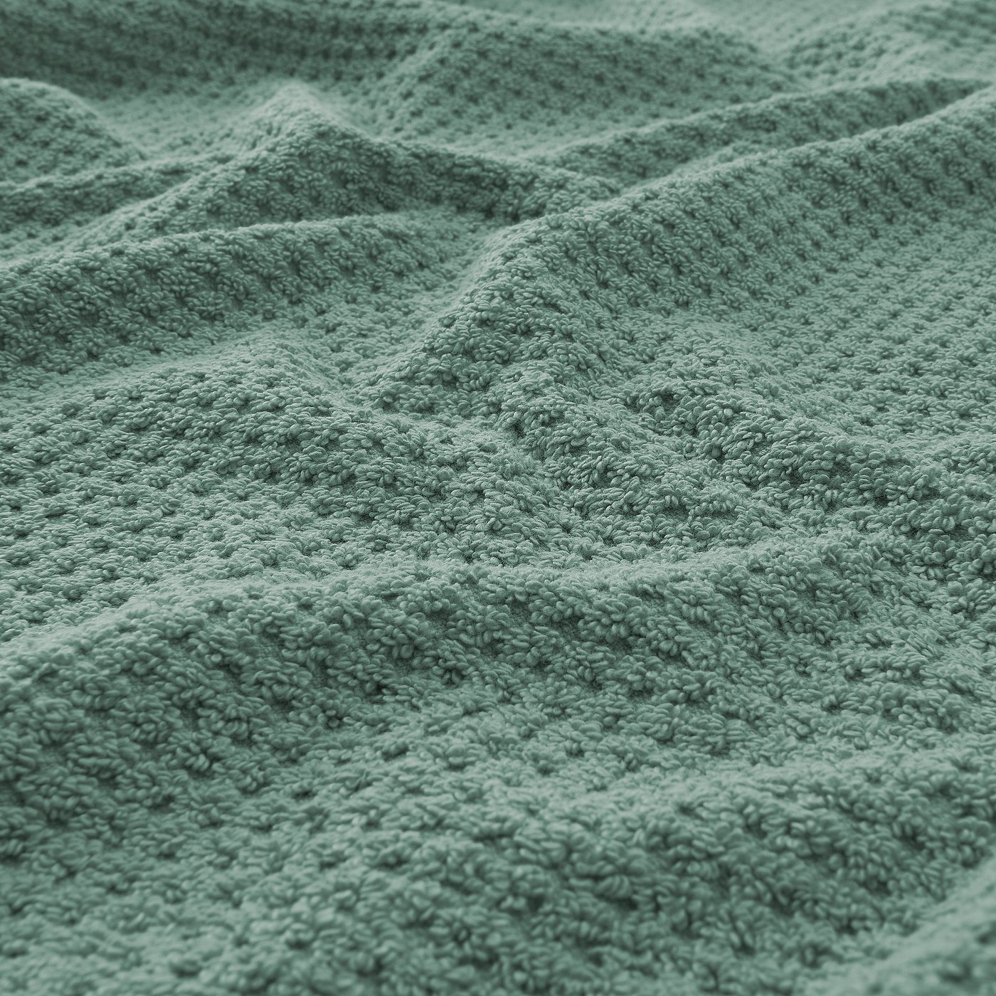 Close-up of soft, plush green towel showcasing its thick, textured weave.