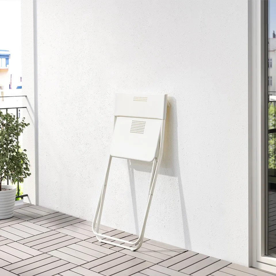 Foldable chair on balcony, white with grid pattern, made of powder-coated steel and plastic.