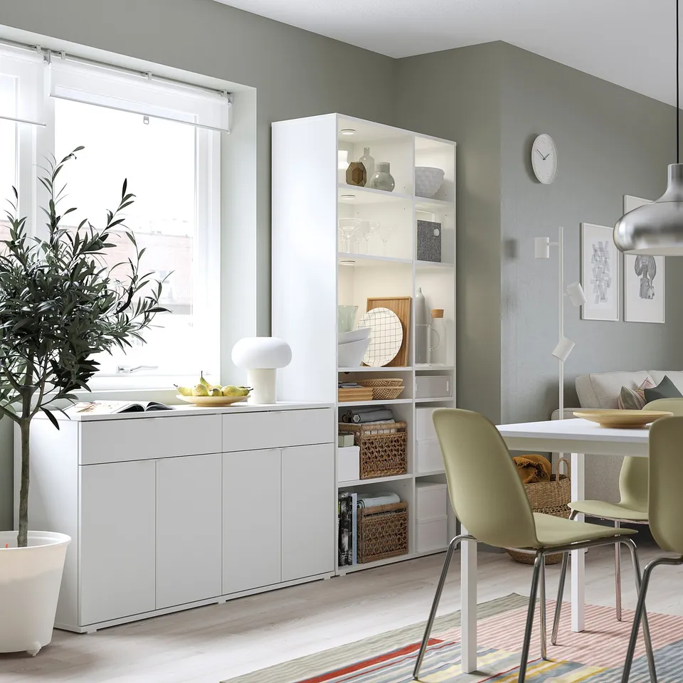 Modern dining area with white VIHALS storage cabinet, green chairs, and kitchenware displayed. Light wood floors and green walls.