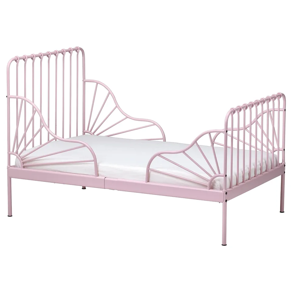 A pink MINNEN metal toddler bed, featuring a decorative wavy headboard and footboard with vertical bars.