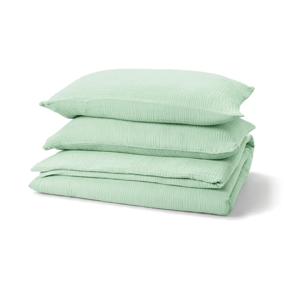 Stack of three light green, soft cotton pillows with wavy texture.