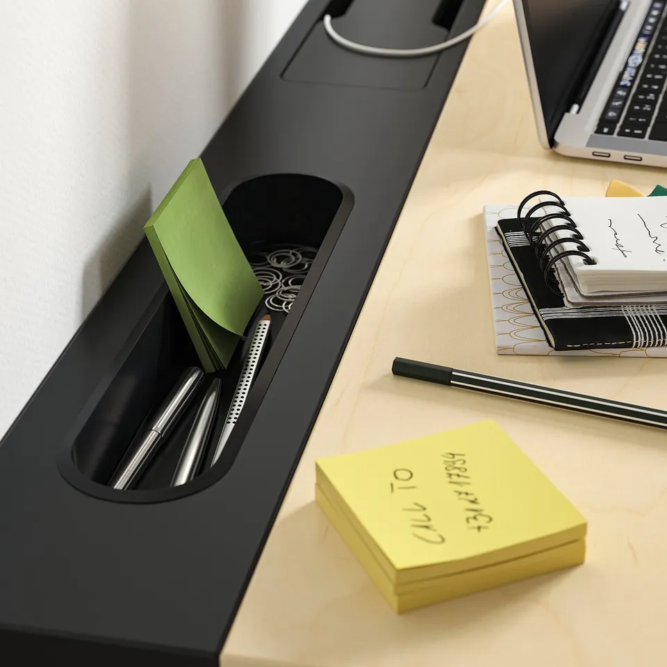 Desk organiser with pens, sticky notes, and notebook. Ideal for office tasks.