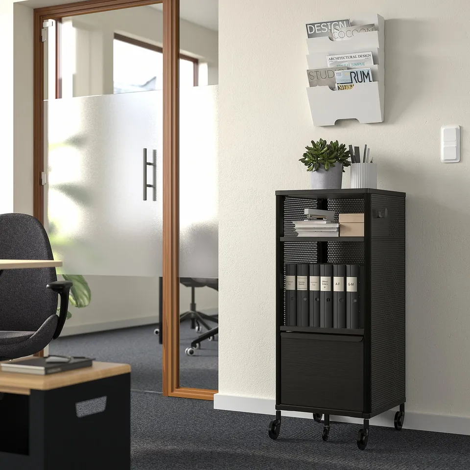 BEKANT storage unit with wheels, books, & binders, pinned papers above, workspace left.