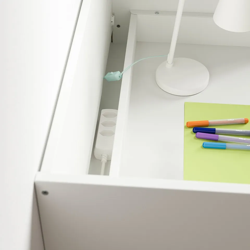 Desk with drawers and accessories. Notebook and pens neatly arranged. Cable management in use.