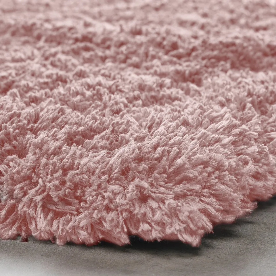 Soft pink shaggy rug close-up, showing thick, fluffy texture.