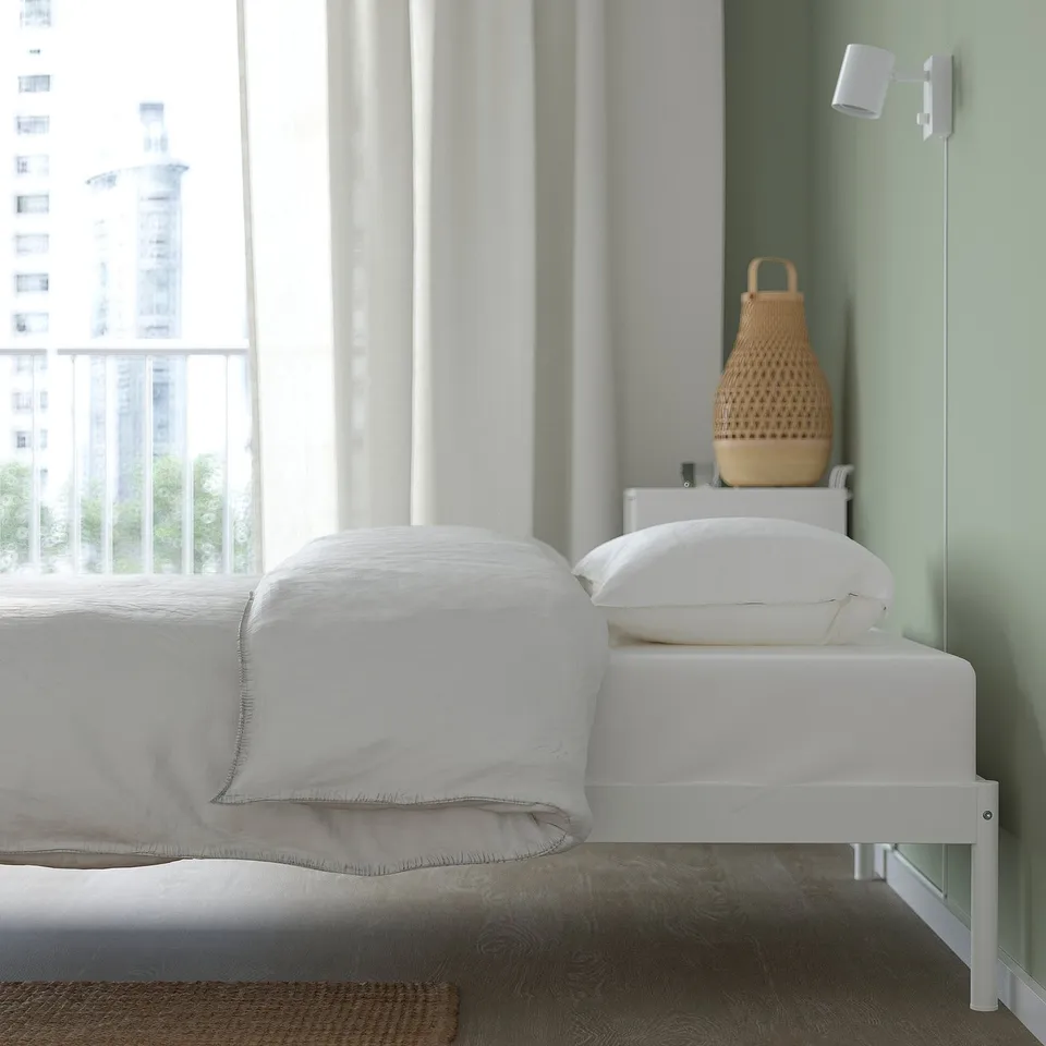 Minimalist bed frame with slatted base for storage under. Modern design with visible screws and vacuum-friendly space.