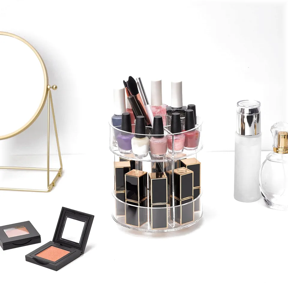 Display of cosmetics: lipstick, nail polish, brushes in a rotating acrylic stand, with mirror and perfume nearby.