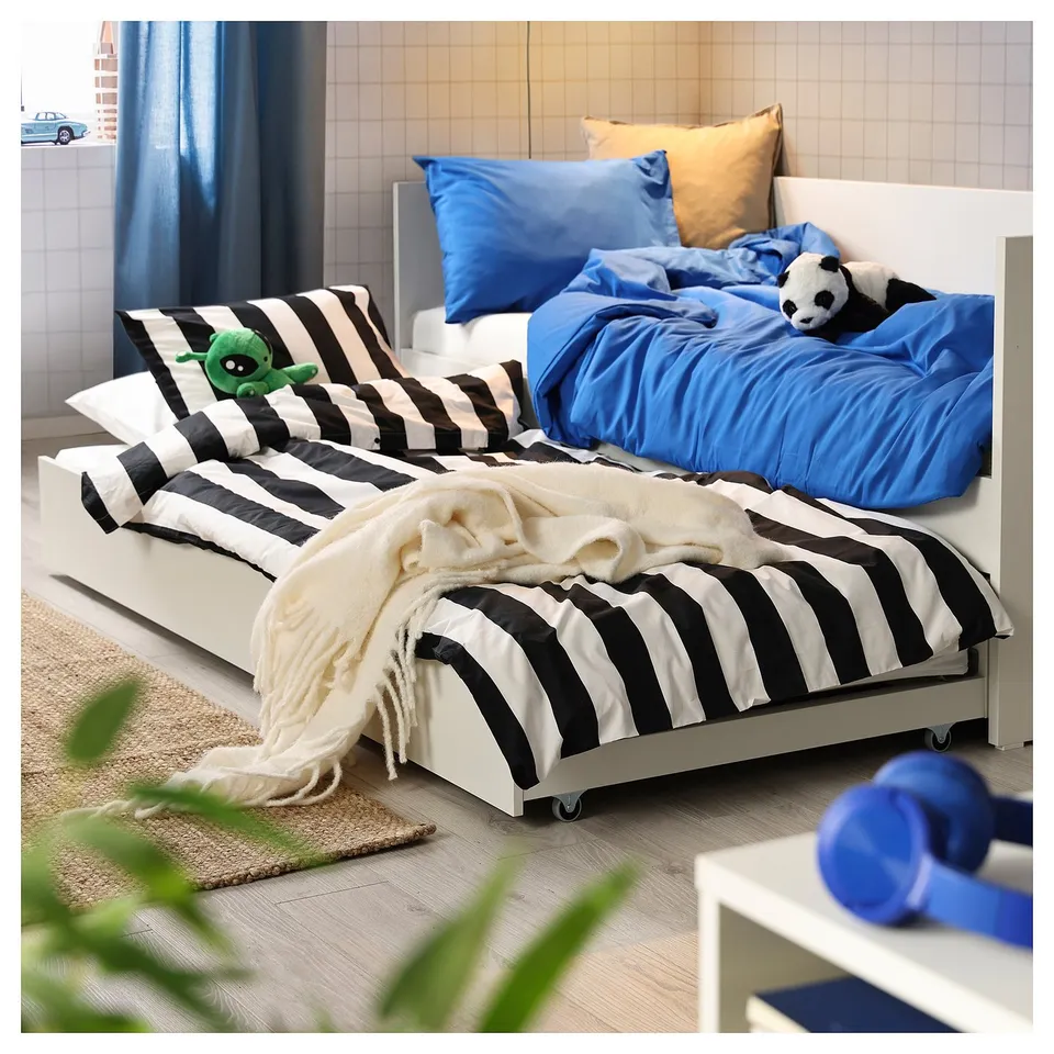 Cosy room with twin beds, one in blue, the other with black & white stripes, plus stuffed animals.
