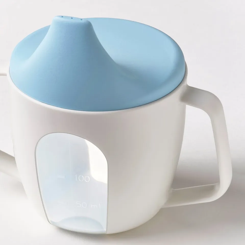 A white beaker with light blue lid and spout, handles on both sides, and a transparent measurement window.
