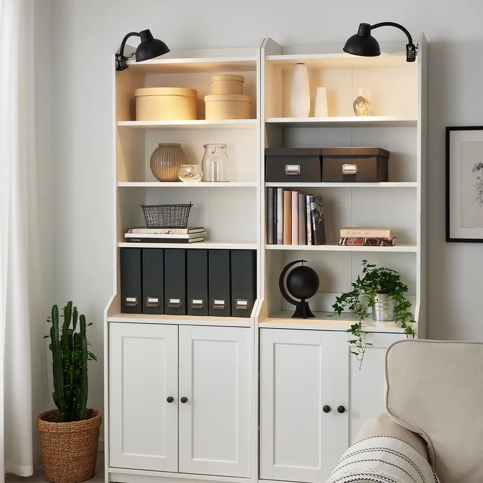 SKURUP lamps on shelves with books, vases, and plants.